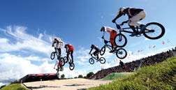 Four men are performing tricks on their bicycles, jumping in the air and riding on ramps. AI generated content