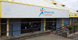 A blue and yellow building with a sign that says “Glasgow Club Castlemilk" on it. AI generated content