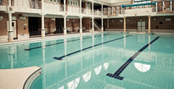 A large indoor pool with a blue tiled bottom and a white tiled top. AI generated content